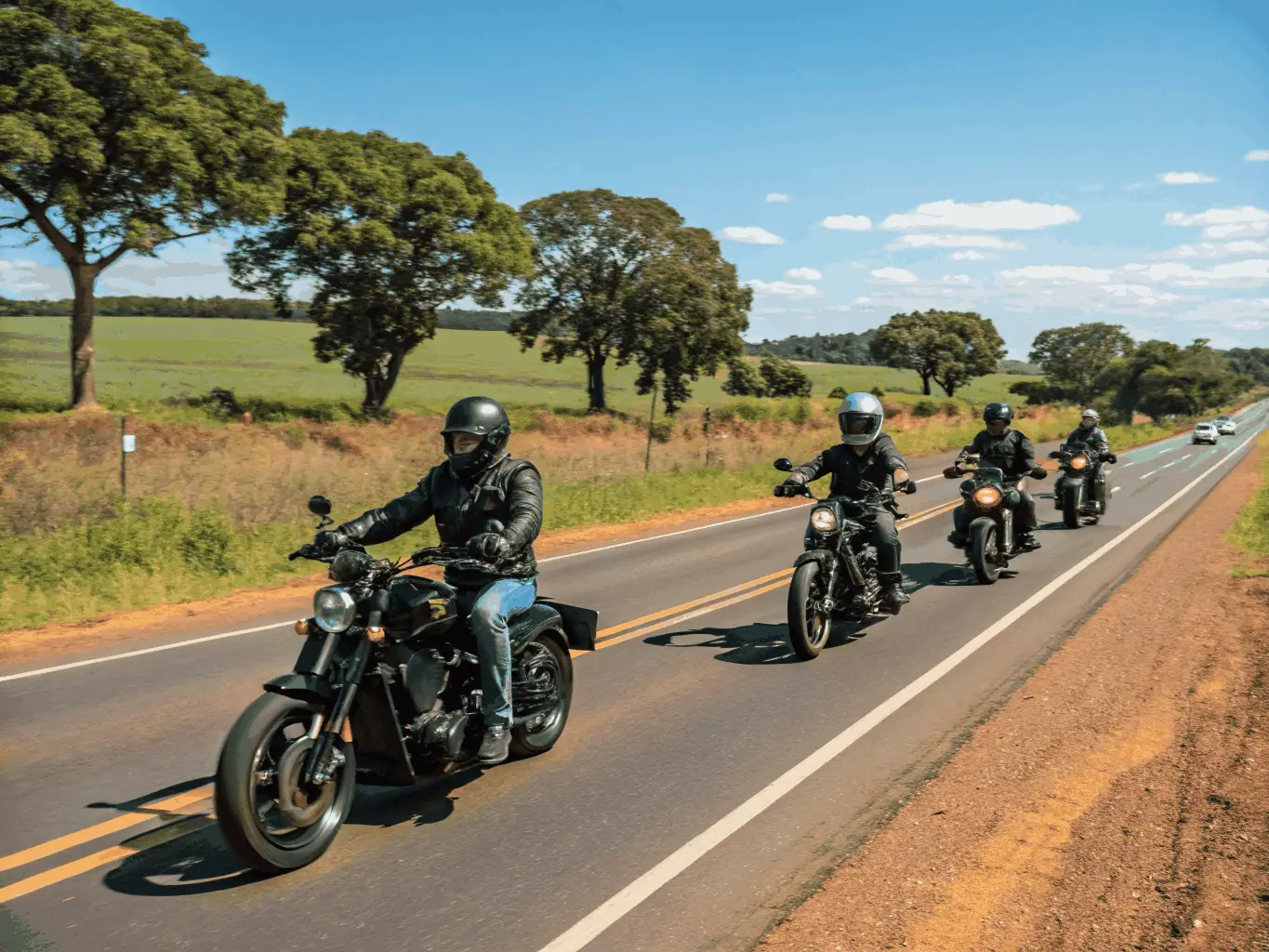A group of motorcyclists riding together on a winding road through a lush forest, showcasing the scenic beauty and camaraderie of BMP's group rides.